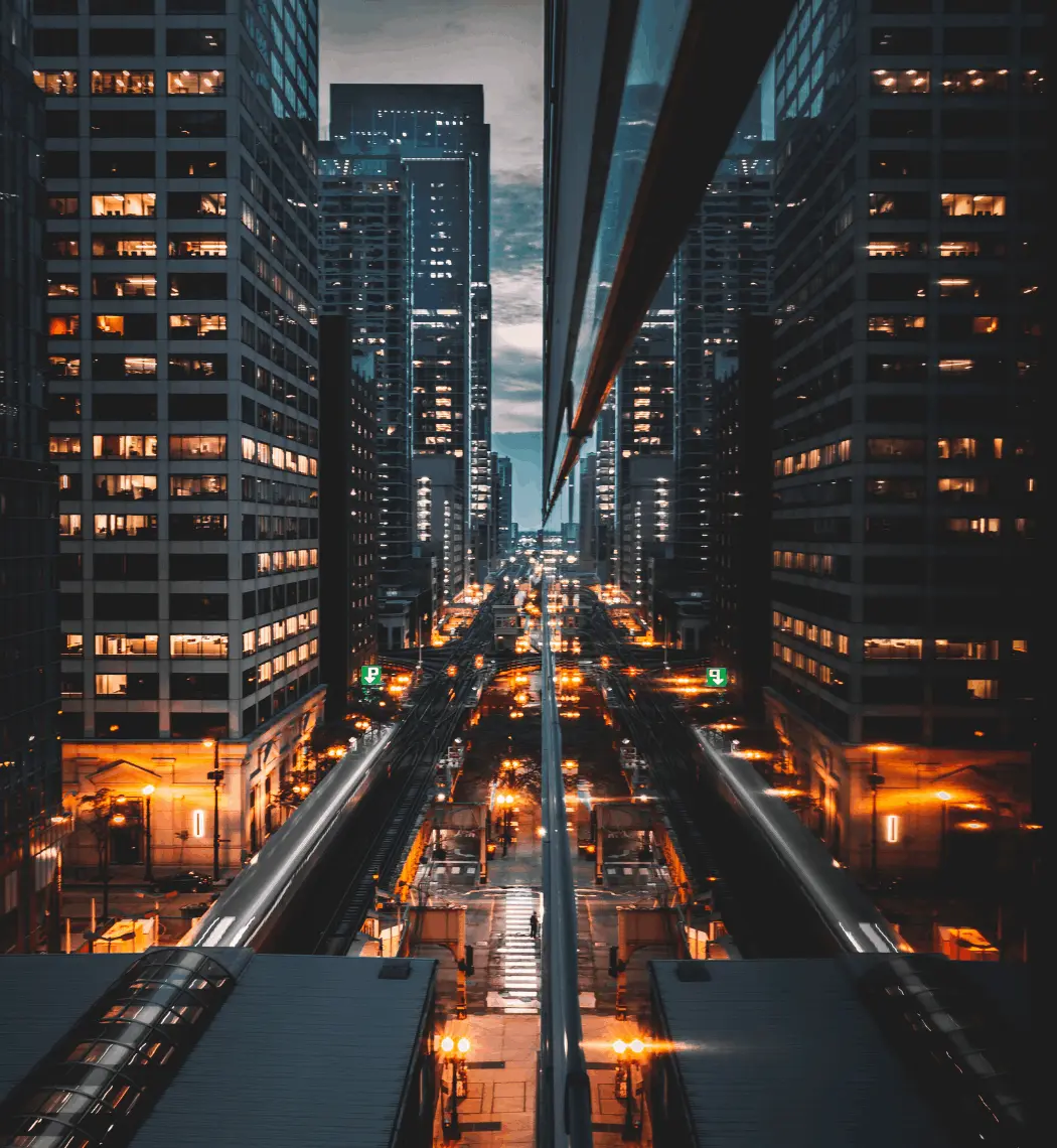 A night time cityscape with a view down a busy street with tall skyscrapers